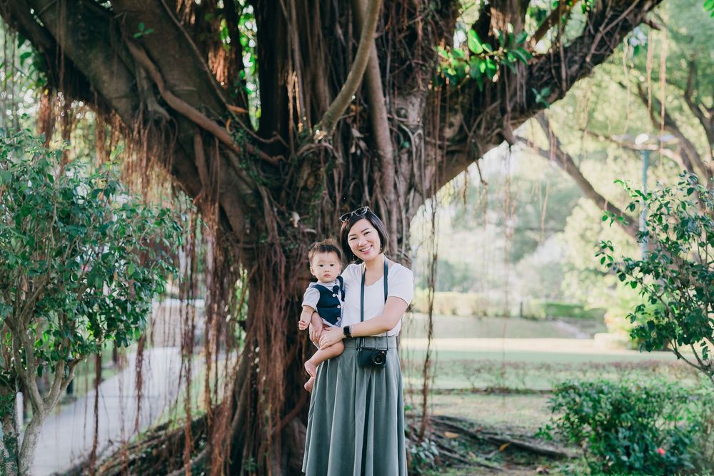 A tender outdoor family moment under a majestic banyan tree with hanging vines.