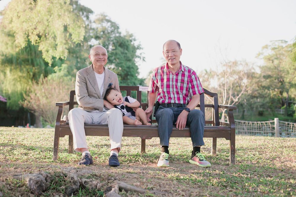 Family enjoying quality time together on a park bench surrounded by autumn leaves at sunset.