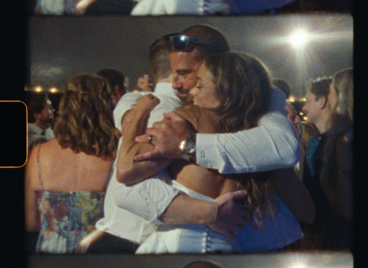 People embrace in an emotional group hug at what appears to be a formal event or celebration.