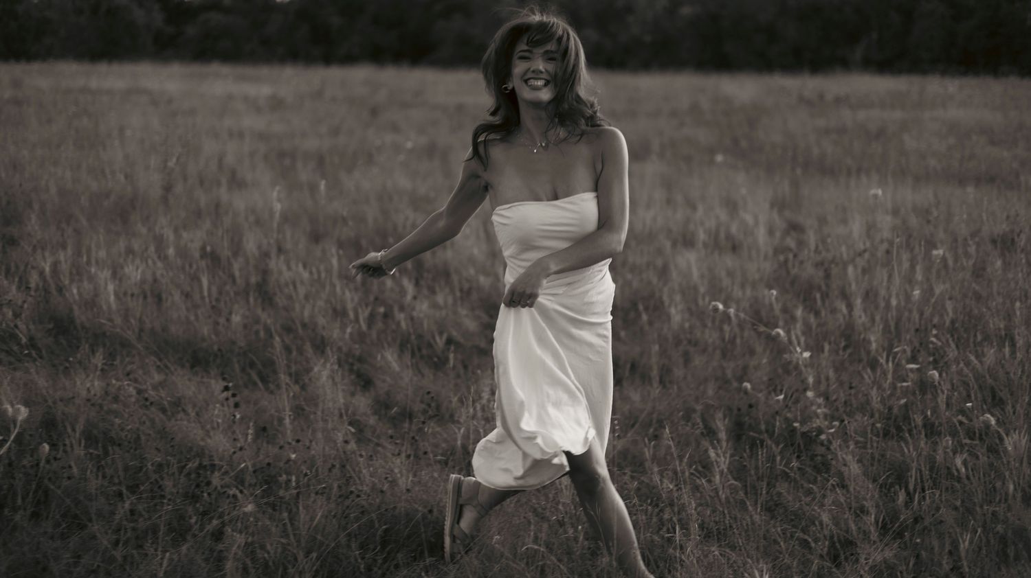 A person in a white dress twirls gracefully through a misty field at sunset creating a dreamy silhouette.