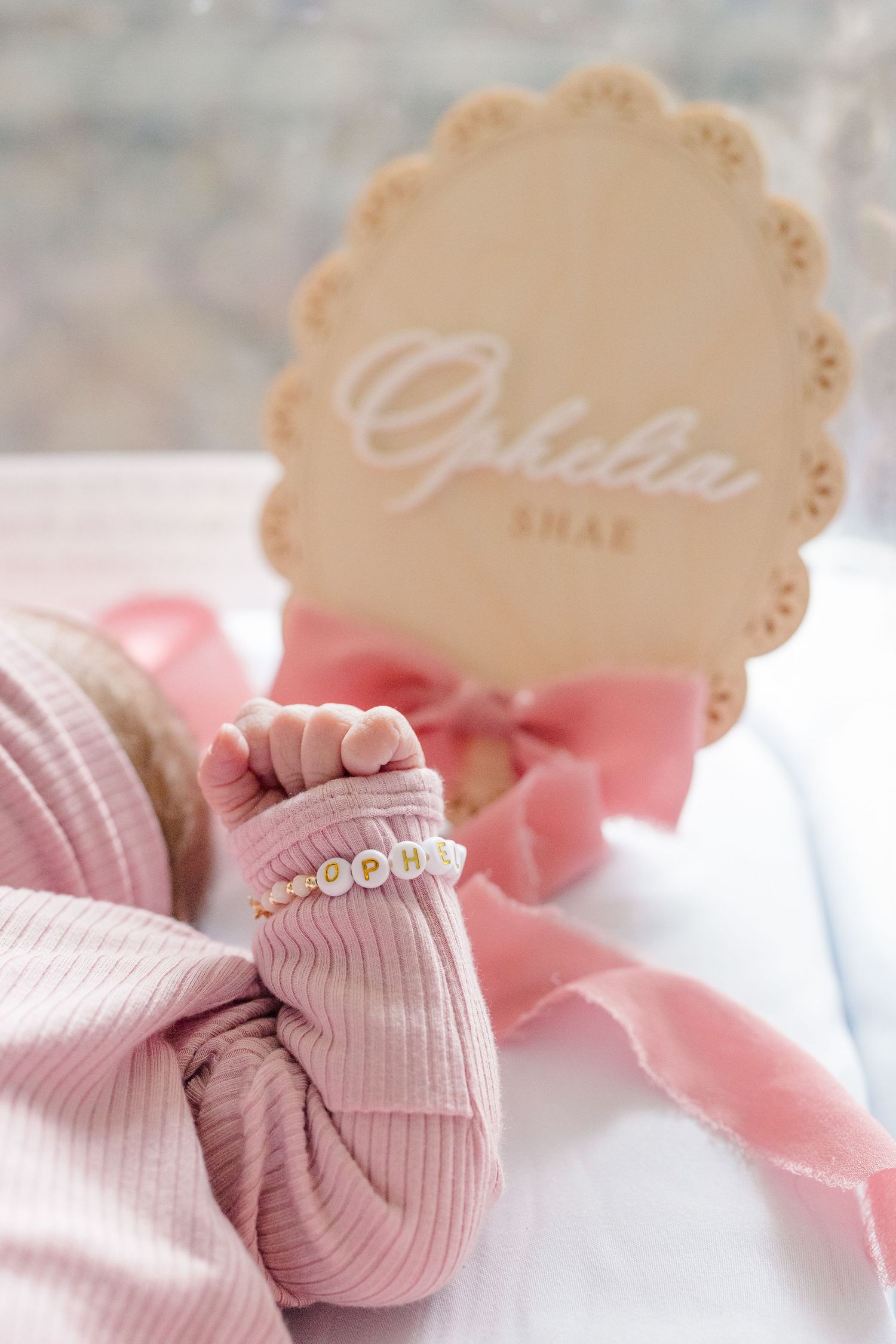 Tiny newborn baby hand with delicate name bracelet in front of wooden name placard during a Fresh 48 session in a Pittsburgh hospital.