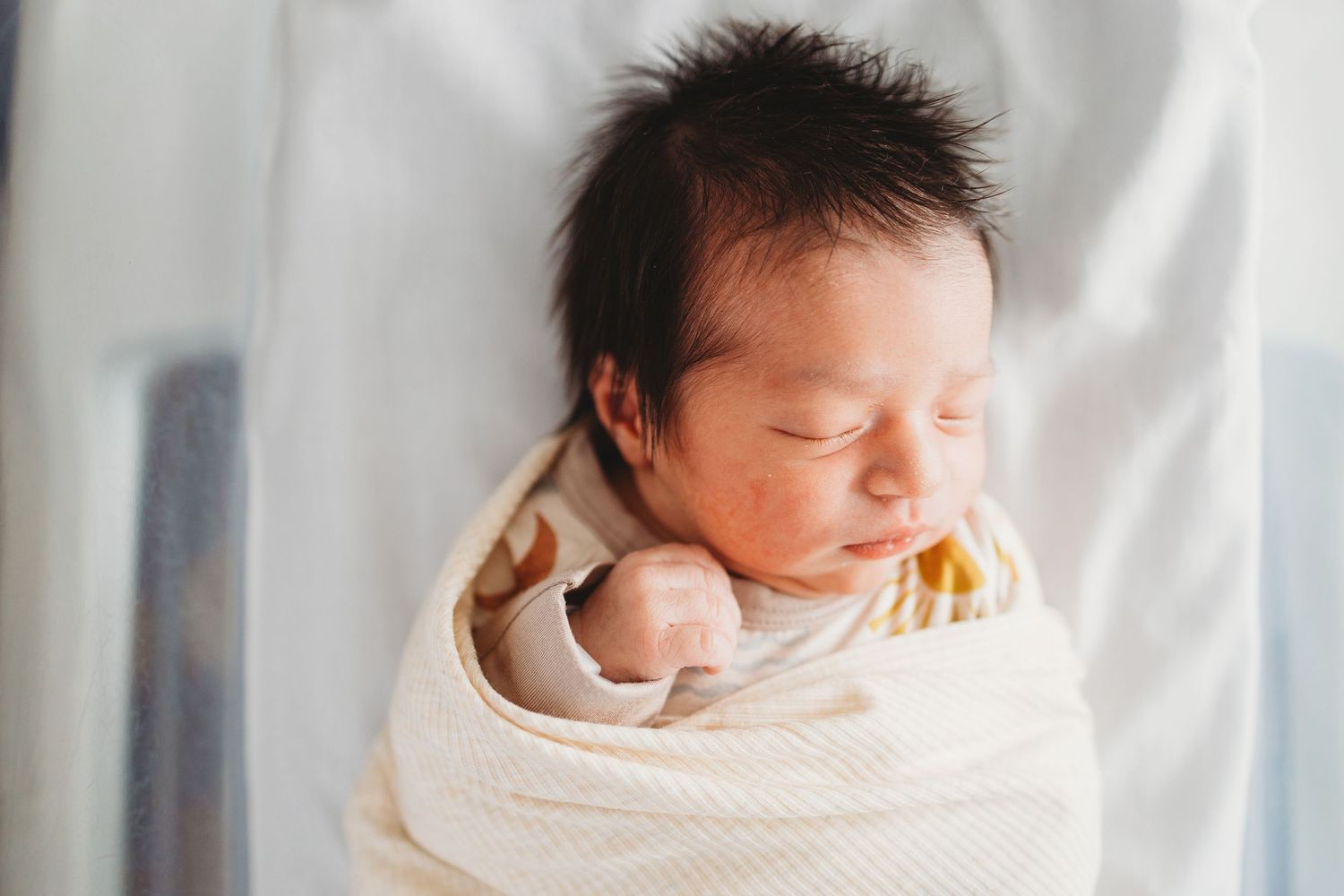 Sleeping newborn baby swaddled in white blanket shown from multiple angles in soft natural light.