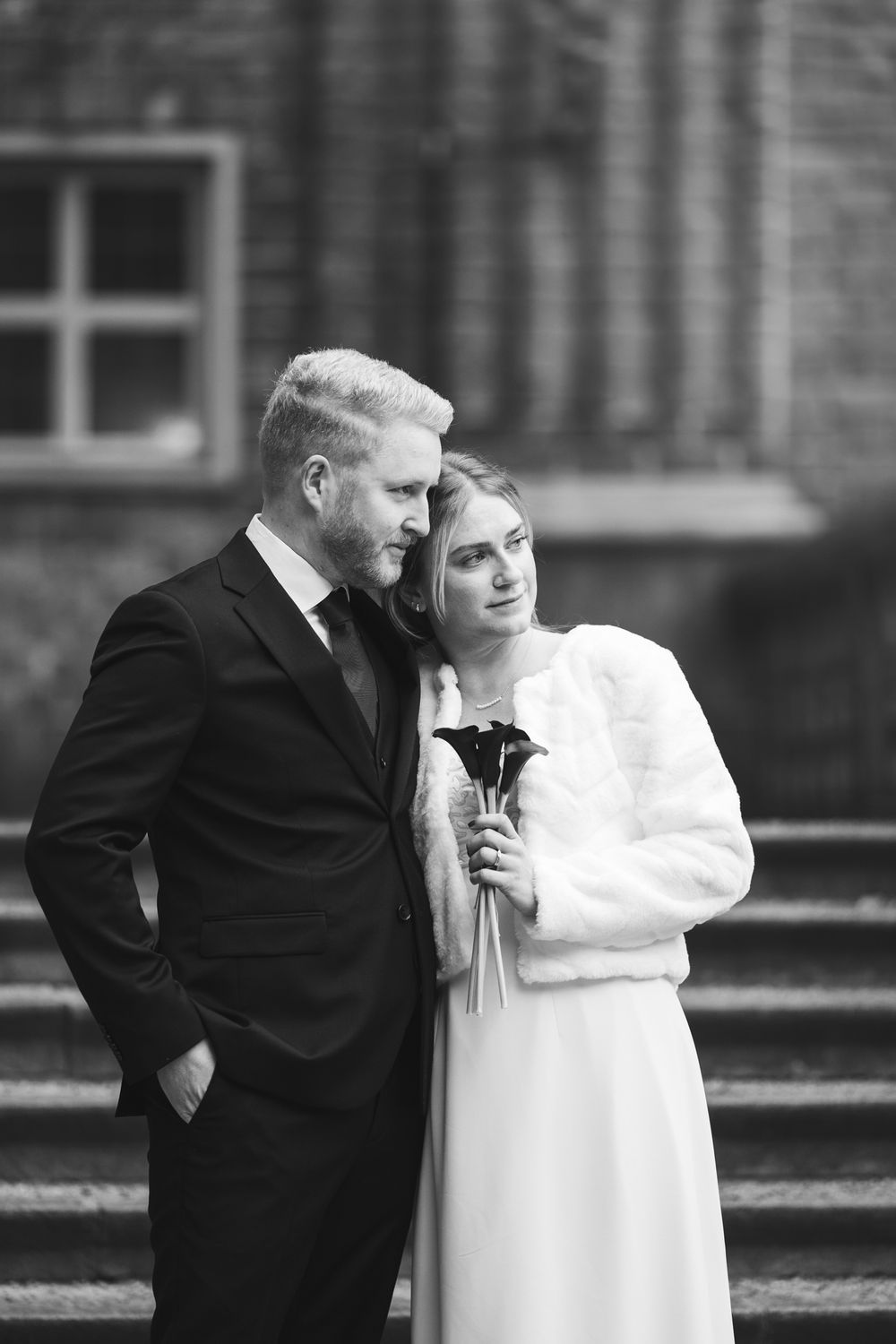 A romantic black and white photo series showing a couple in formal attire embracing on stone steps.