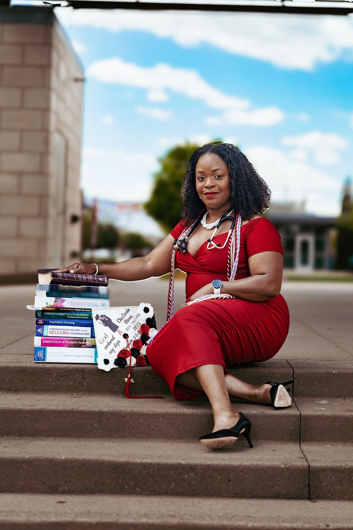 A person in a red dress poses with stacks of books on concrete steps in a creative outdoor photo series.