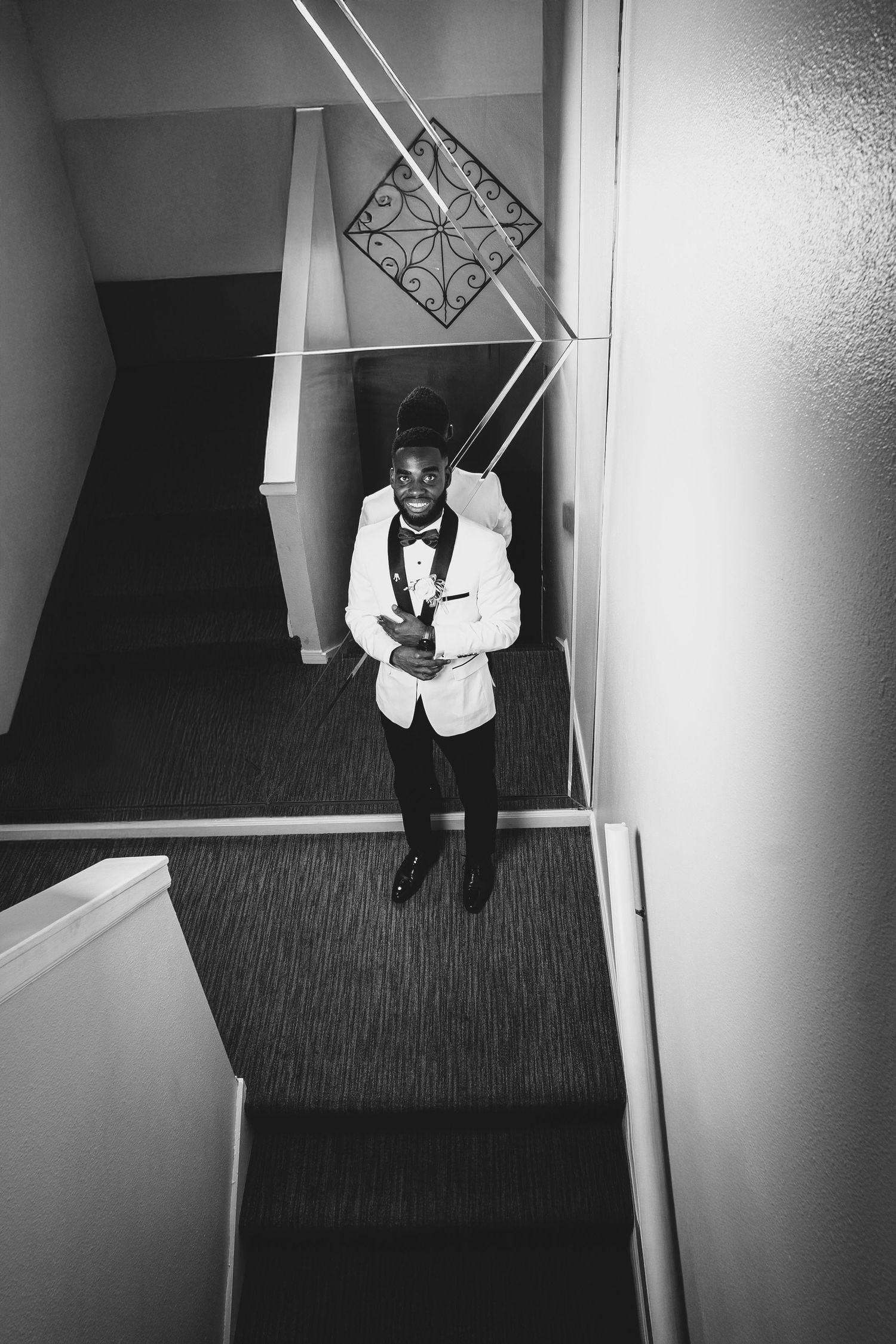 Black and white stairwell portrait of groom in formal attire with geometric wall details.