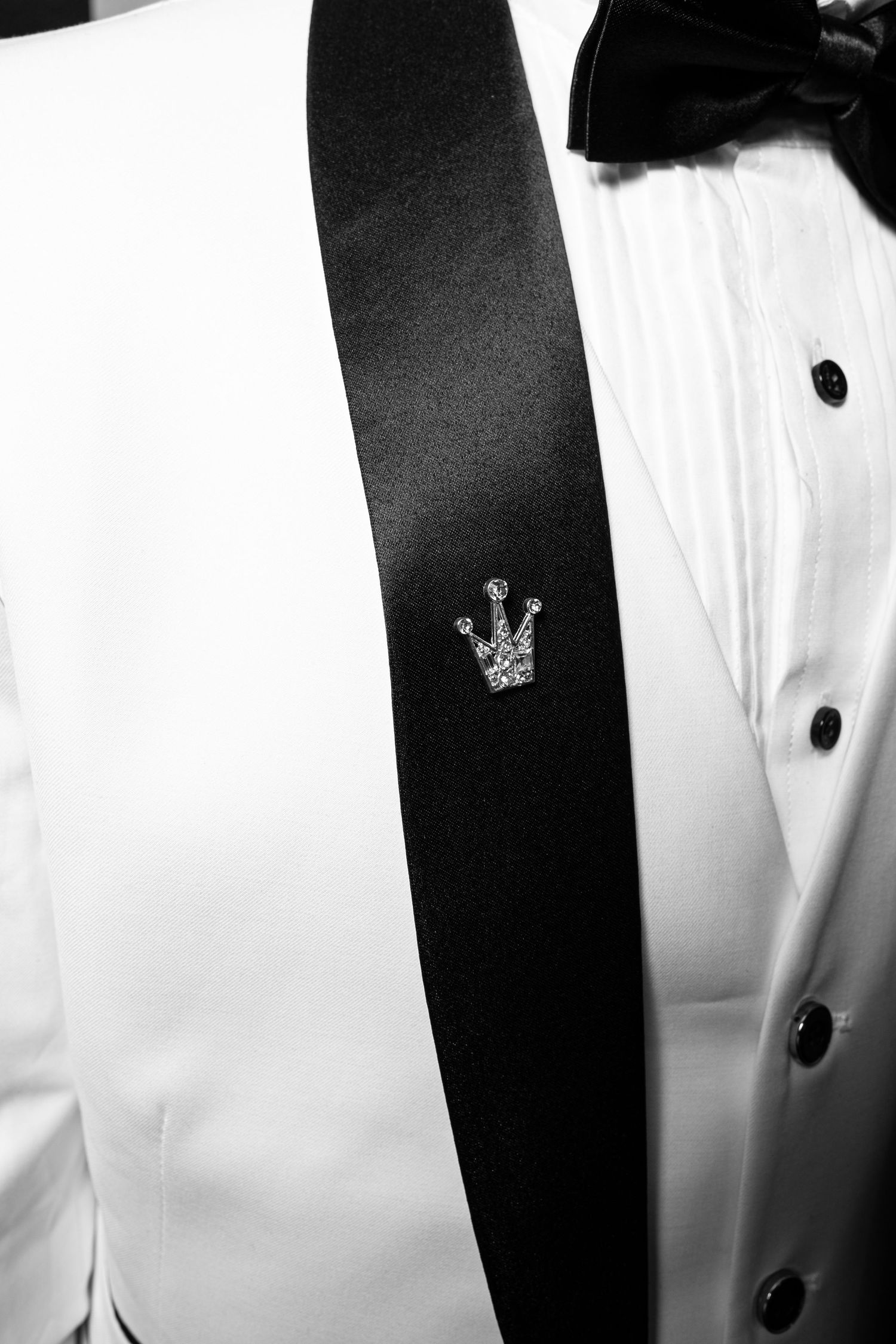 Black and white close-up of formal attire showing alternating dark tuxedo jackets and white dress shirts with buttons.
