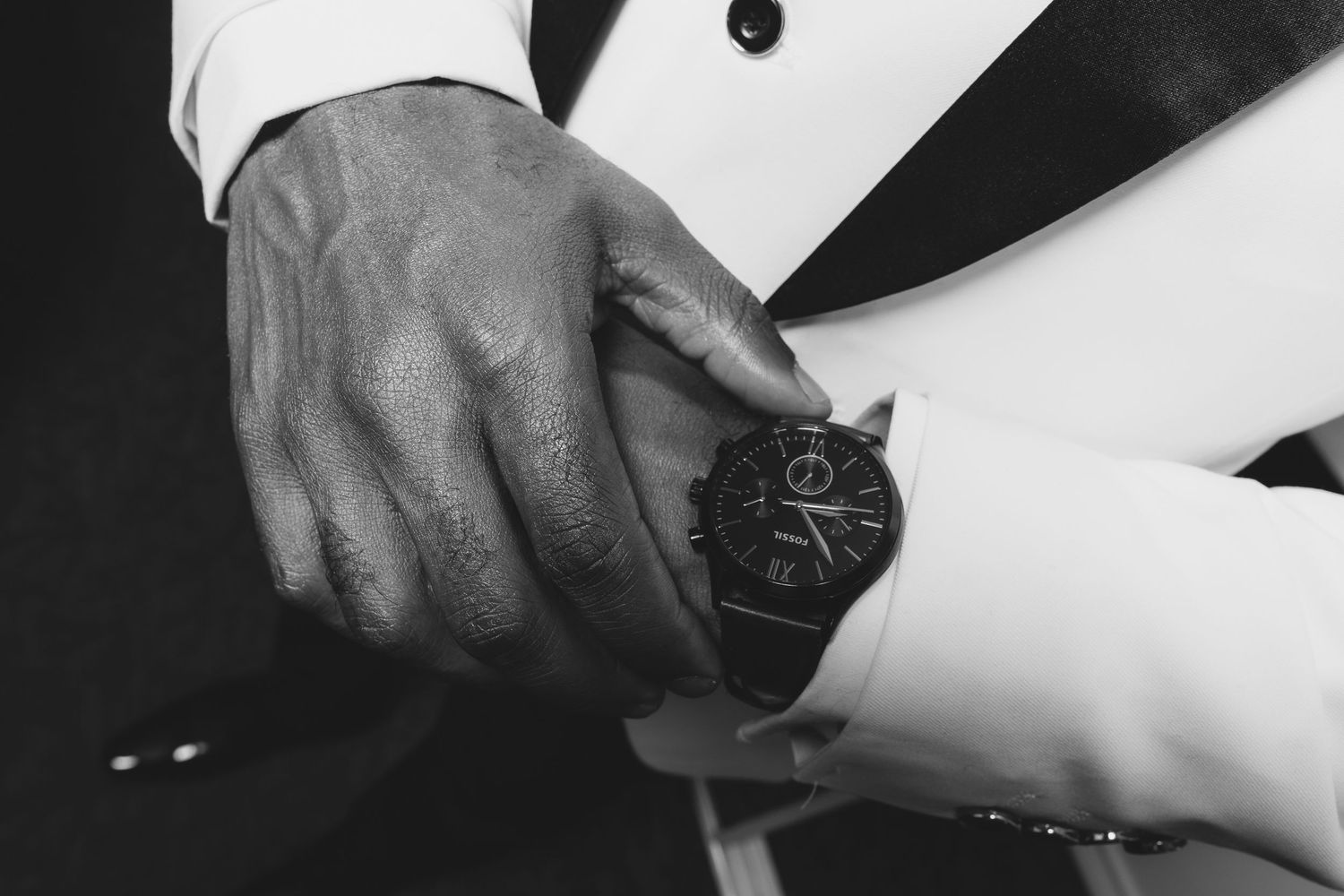 A black and white close-up of hands opening a bottle of champagne.