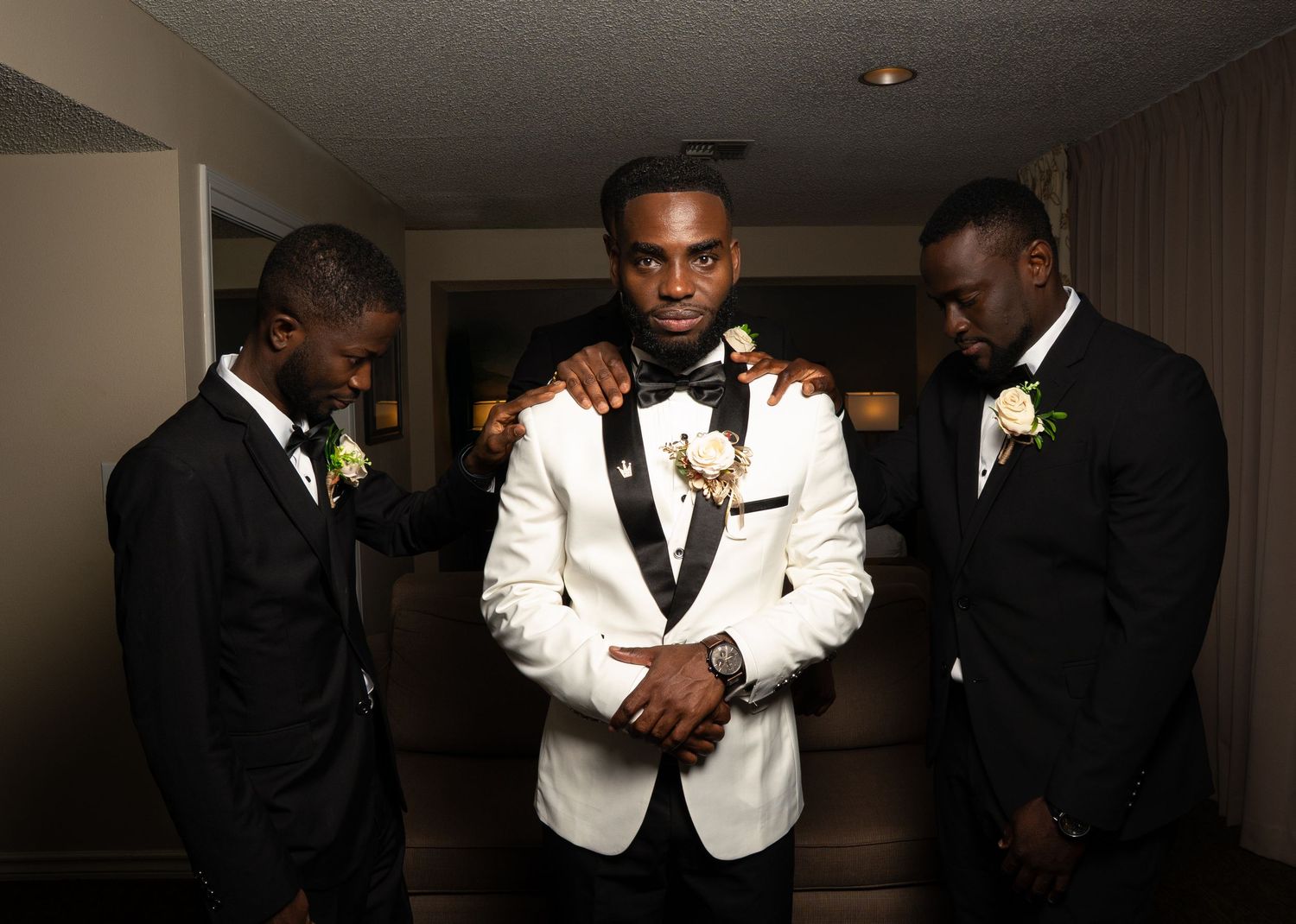 A group of men in formal black and white attire pose together in a dimly lit room.