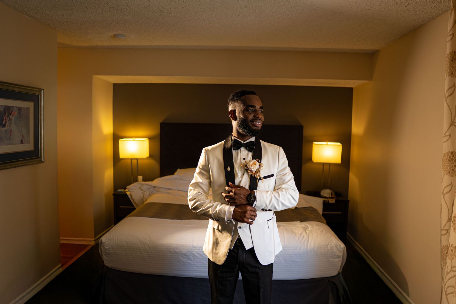 A panoramic view of a hotel room interior with warm lighting, white bedding, and contemporary furnishings.