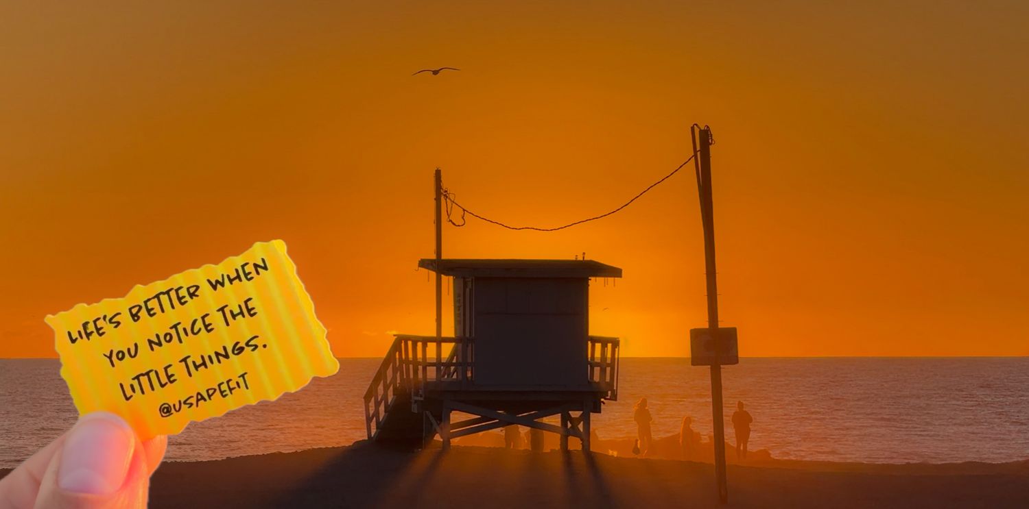 Dramatic orange sunset sky over a silhouetted cityscape with power lines and buildings creating a moody urban landscape.