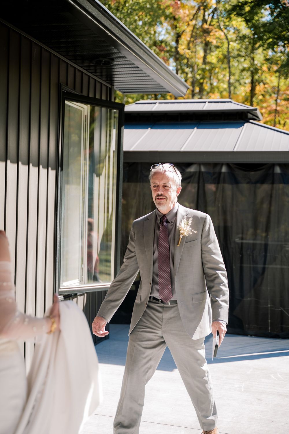 A person in a light gray suit dances and moves playfully across a covered outdoor patio area.