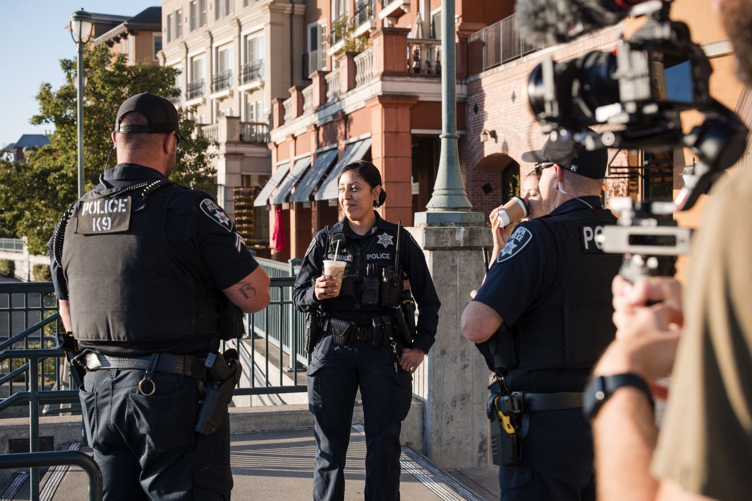 Law enforcement officers gathered with coffee in hand on a city street.