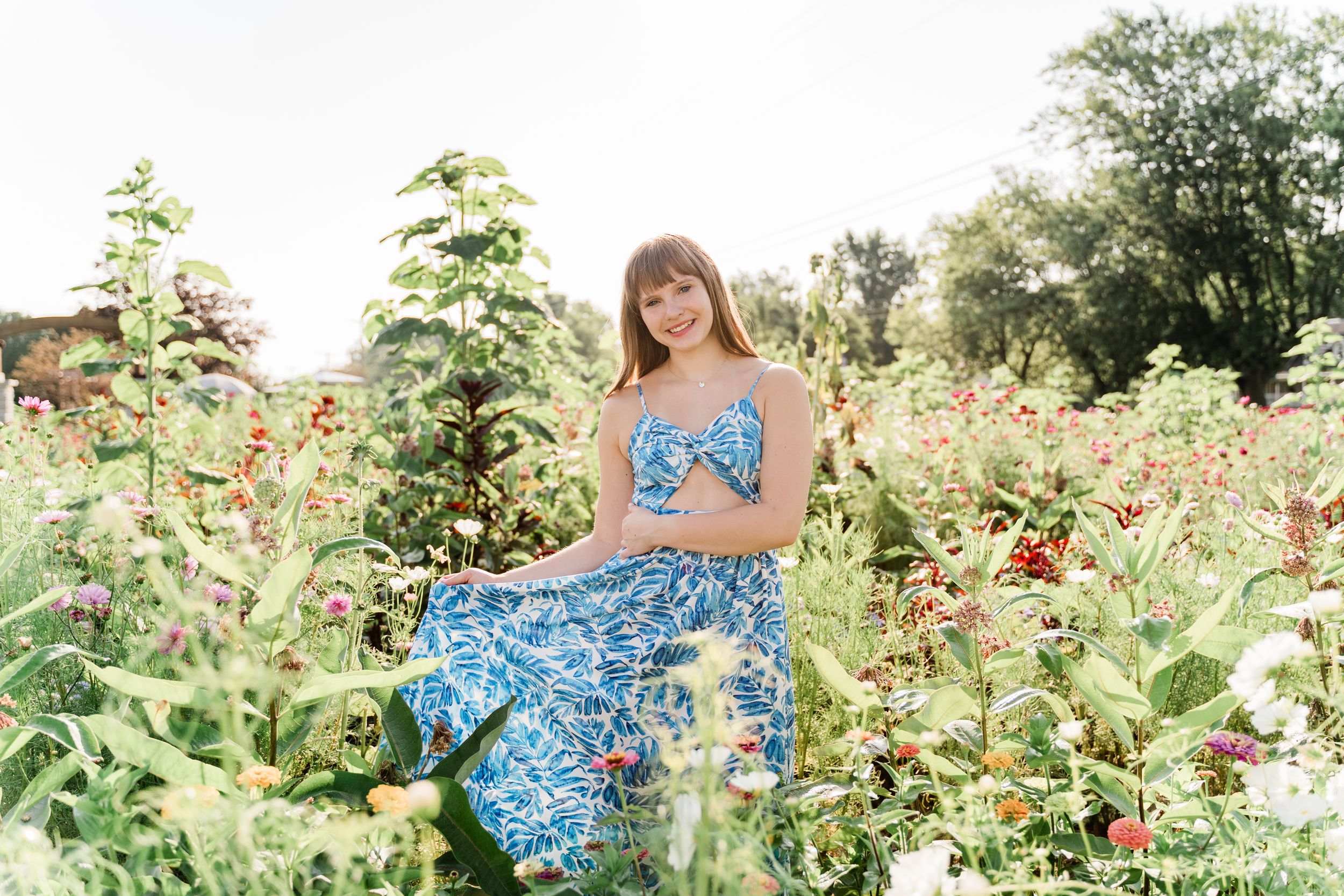 Woman in blue floral dress explores a vibrant sunflower garden on a bright summer day.