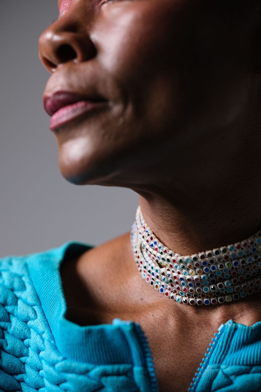 Close-up of sparkly silver choker necklace against bright turquoise fabric.