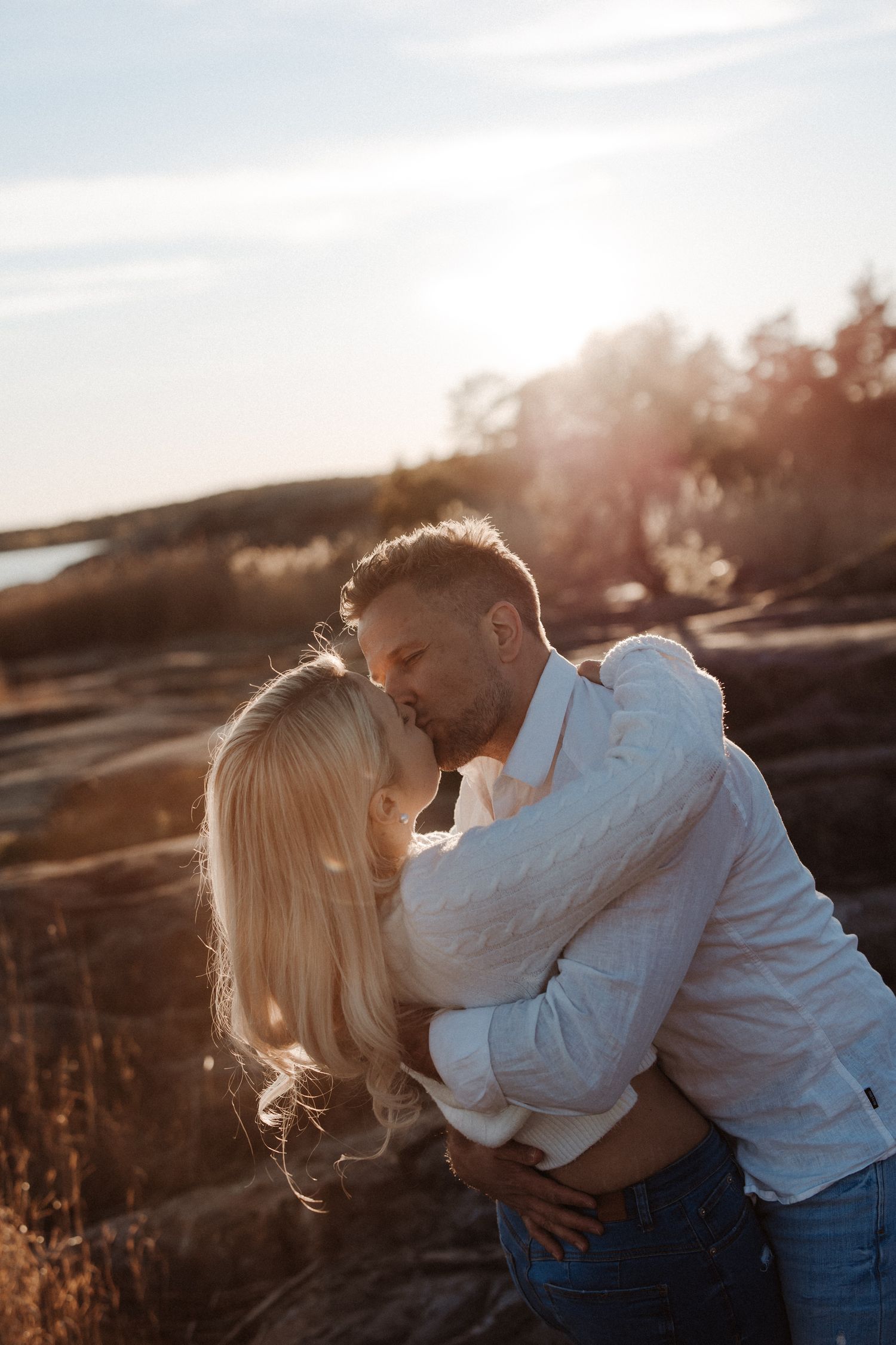 A romantic couple in beige sweaters share tender moments against a blue sky backdrop in a series of intimate photographs.