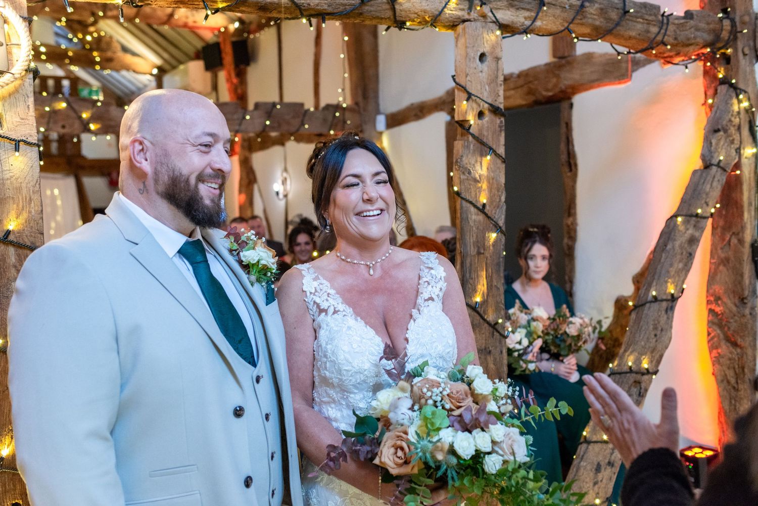 Newlyweds smiling during a rustic barn ceremony at The Plough Inn, Eaton; professional Cheshire wedding photography by Michael Pardoe