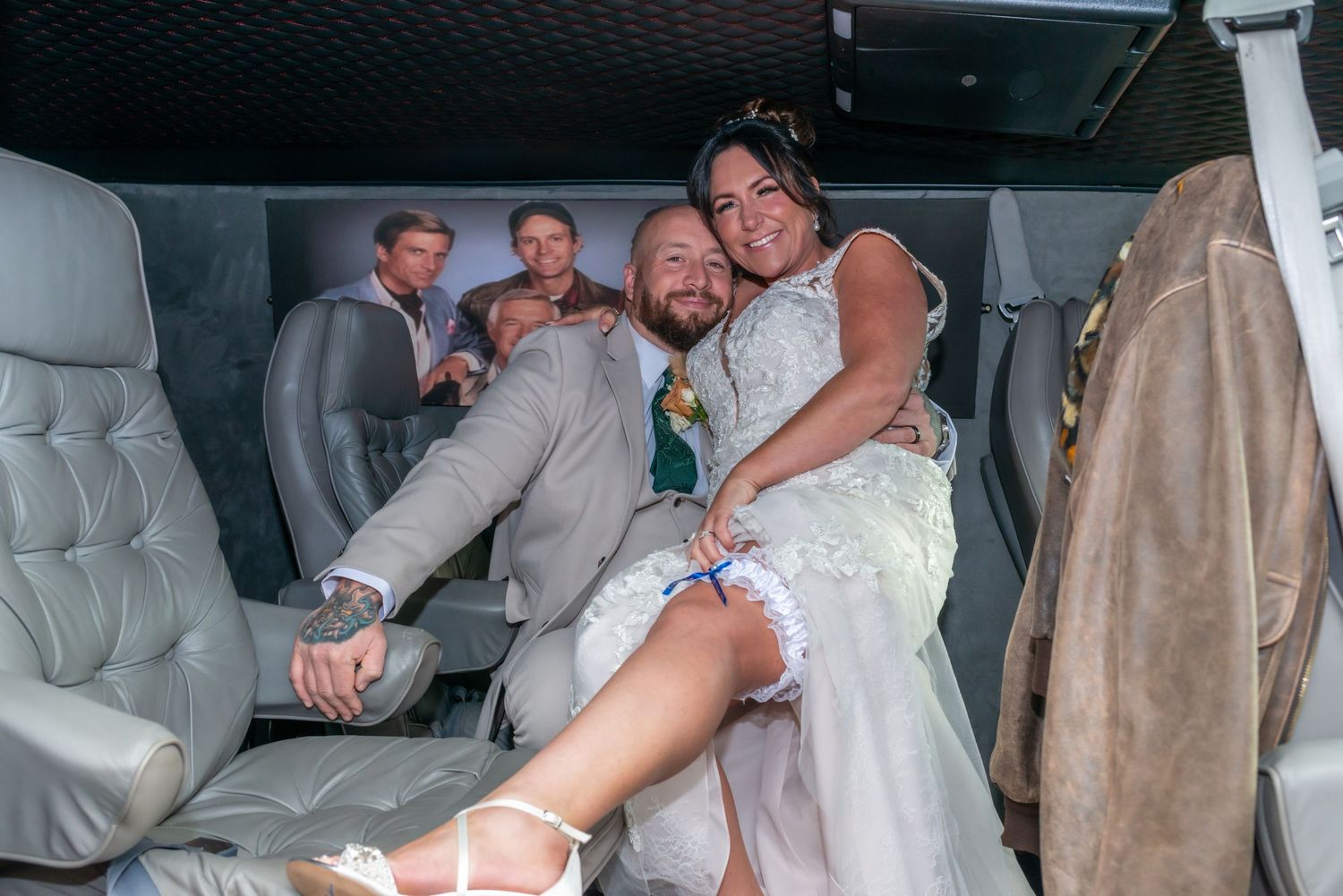 Newlyweds sitting in the back of a decorated wedding car with festive decorations.