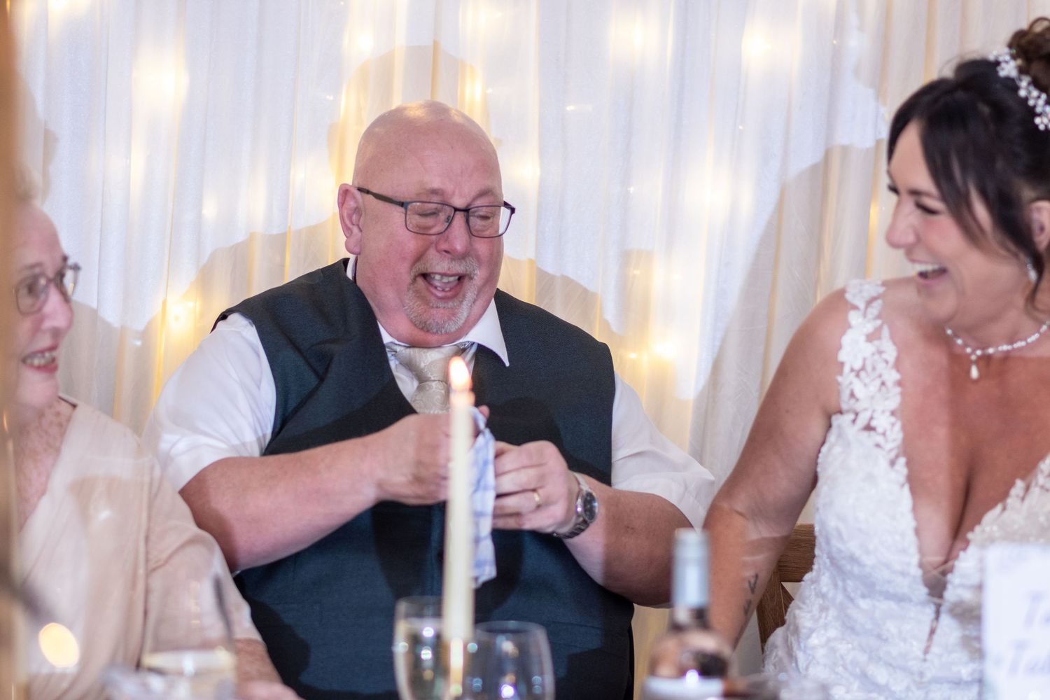 Wedding reception guest laughing while giving a speech at the celebration dinner.