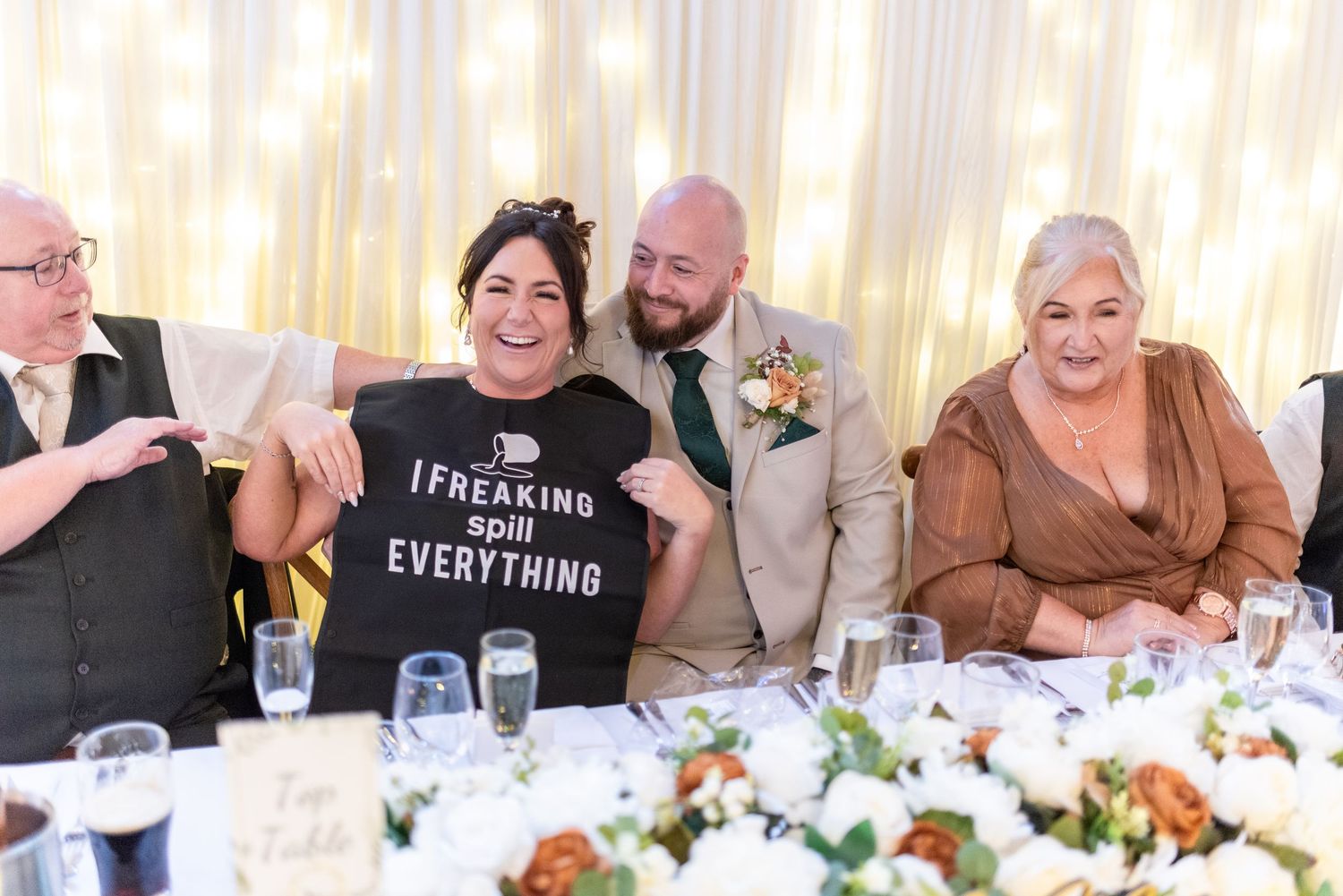 Wedding reception guests sharing laughs at the decorated dinner table.