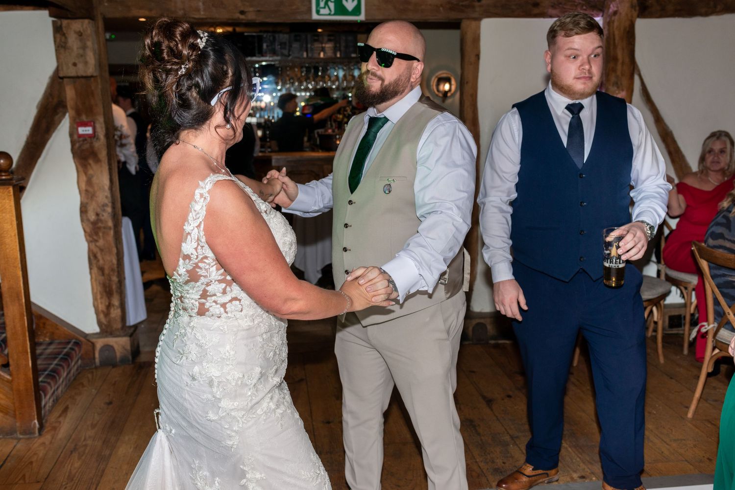 Guests dancing and celebrating at a rustic barn wedding reception with wooden beams.