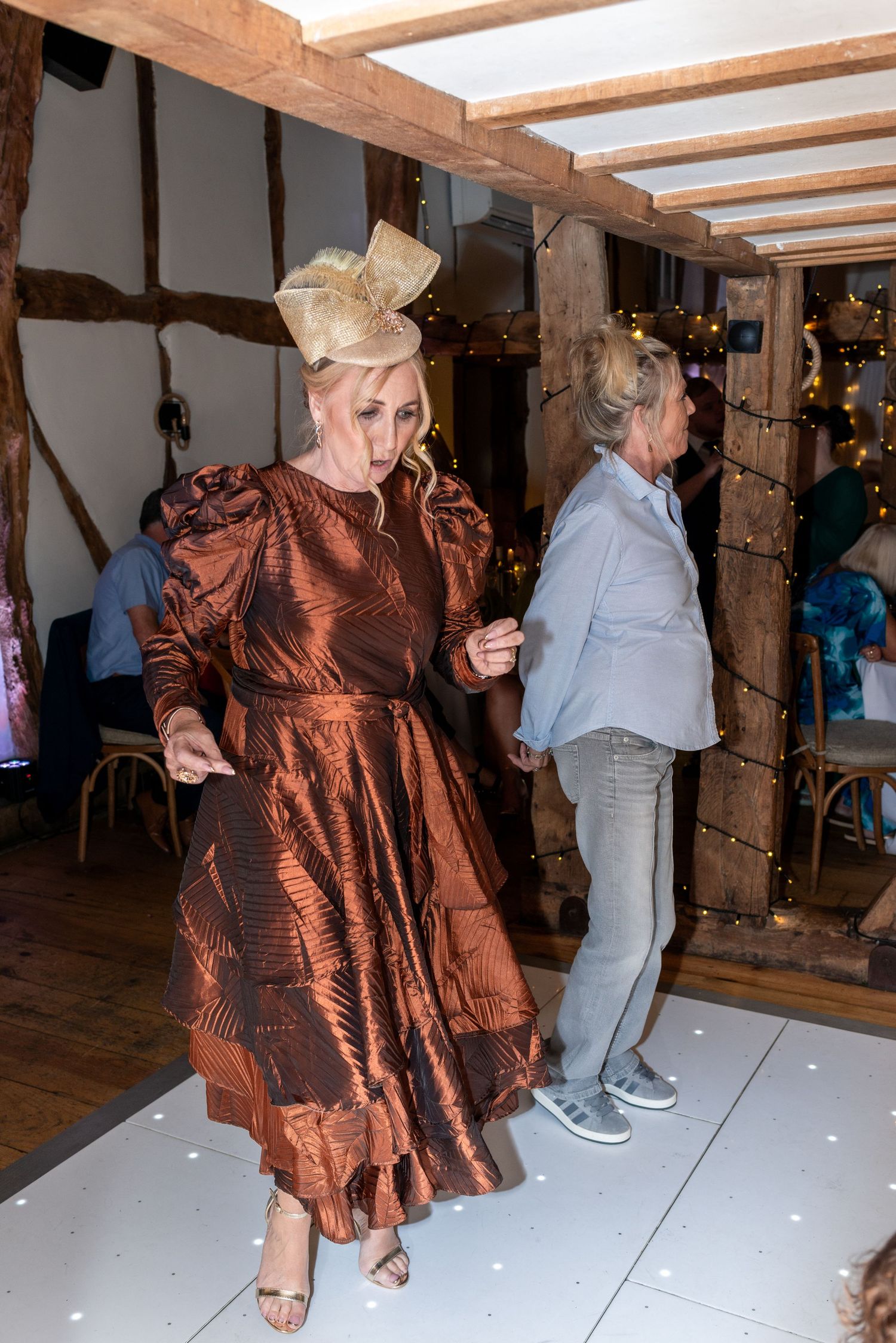 Dancers in formal attire move across illuminated dance floor at indoor reception venue.