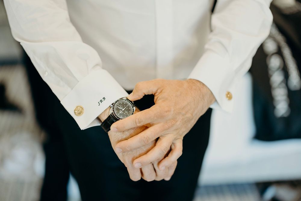 Close-up of hands adjusting formal white shirt cuffs and buttons.