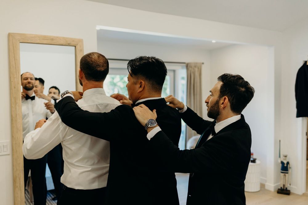 Group of groomsmen raising glasses for a celebratory toast at a wedding.