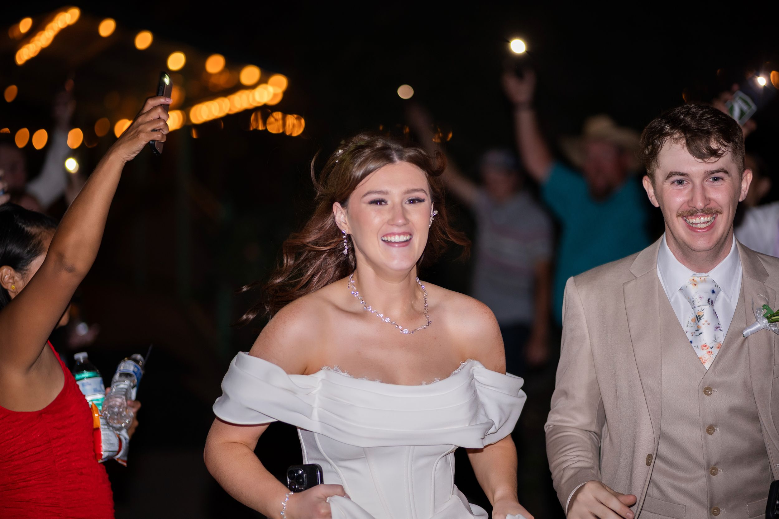 Wedding guests dancing and celebrating at a lively reception party under warm lighting.