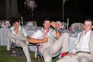 A group of wedding guests in khaki pants relax in chairs during an outdoor reception celebration.