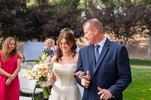 A couple shares a romantic moment during their outdoor wedding celebration with guests looking on.