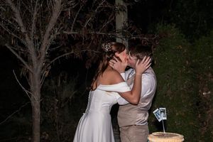 Newlyweds share an intimate dance moment outdoors at night surrounded by trees.