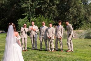 Wedding party stands in a row on grassy lawn during outdoor celebration with bridesmaids and groomsmen.