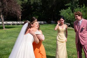 A group of wedding guests dancing and celebrating outdoors on a sunny day in a grassy area.