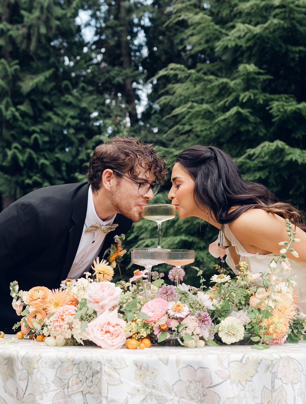 Romantic wedding table setting with lush floral arrangements and delicate white linens outdoors.