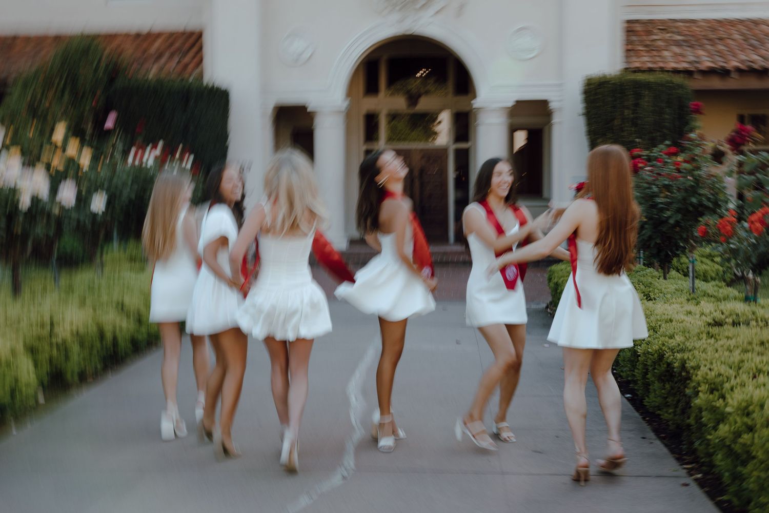 Graduates and best friends in red stoles have fun taking their group graduation photos together.