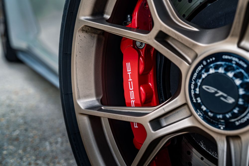 Close-up detail of luxury car wheel with red brake caliper and silver alloy rim design.