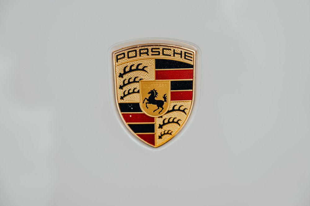 A collection of Porsche car emblems showing the iconic gold and black shield logo with prancing horse design.