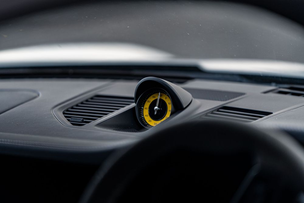 Sleek black car dashboard design featuring modern angular vents and minimalist controls in dark lighting.