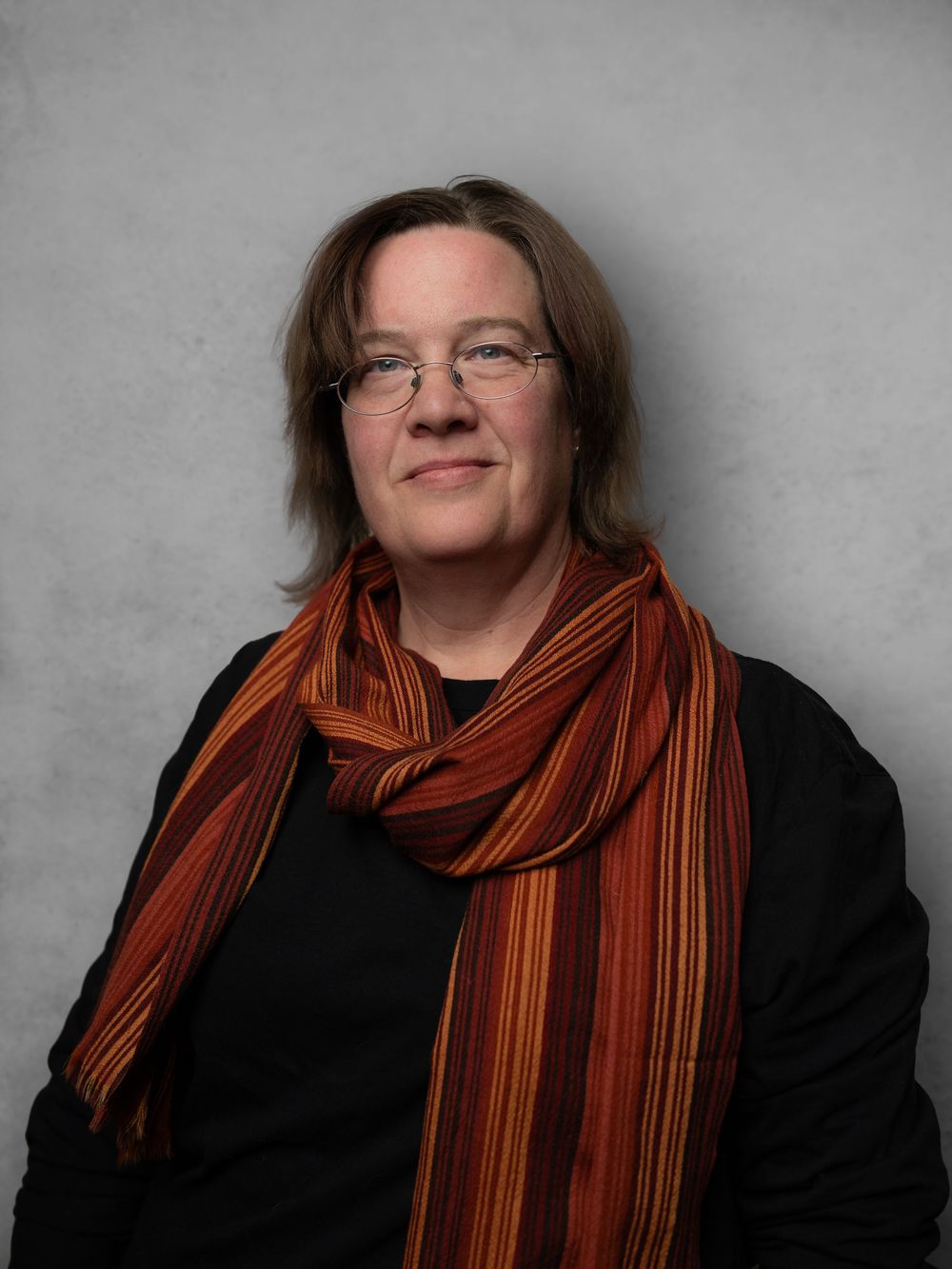 Portrait series showing a person in a black top and orange striped scarf against a gray background.