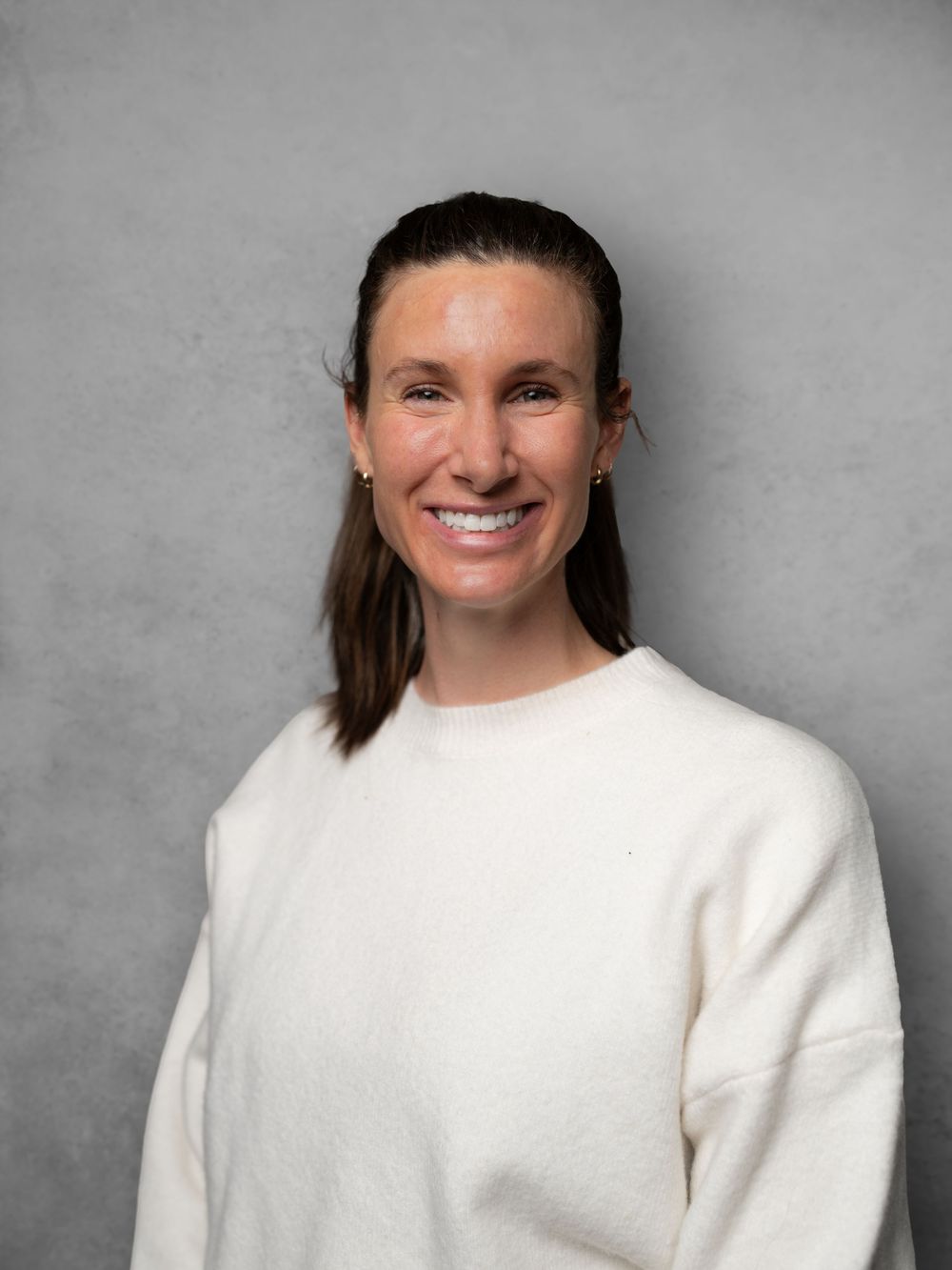 Professional headshot portrait series showing expressions against a gray background wearing a white sweater.