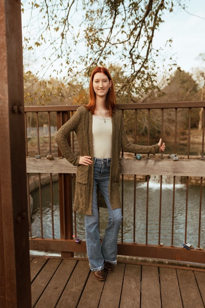 People enjoying a casual autumn day on a wooden deck overlooking a serene lake with fall foliage in the background.