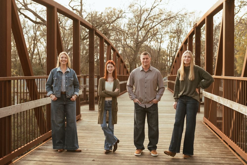 Family walking together on a wooden bridge during autumn sunset.
