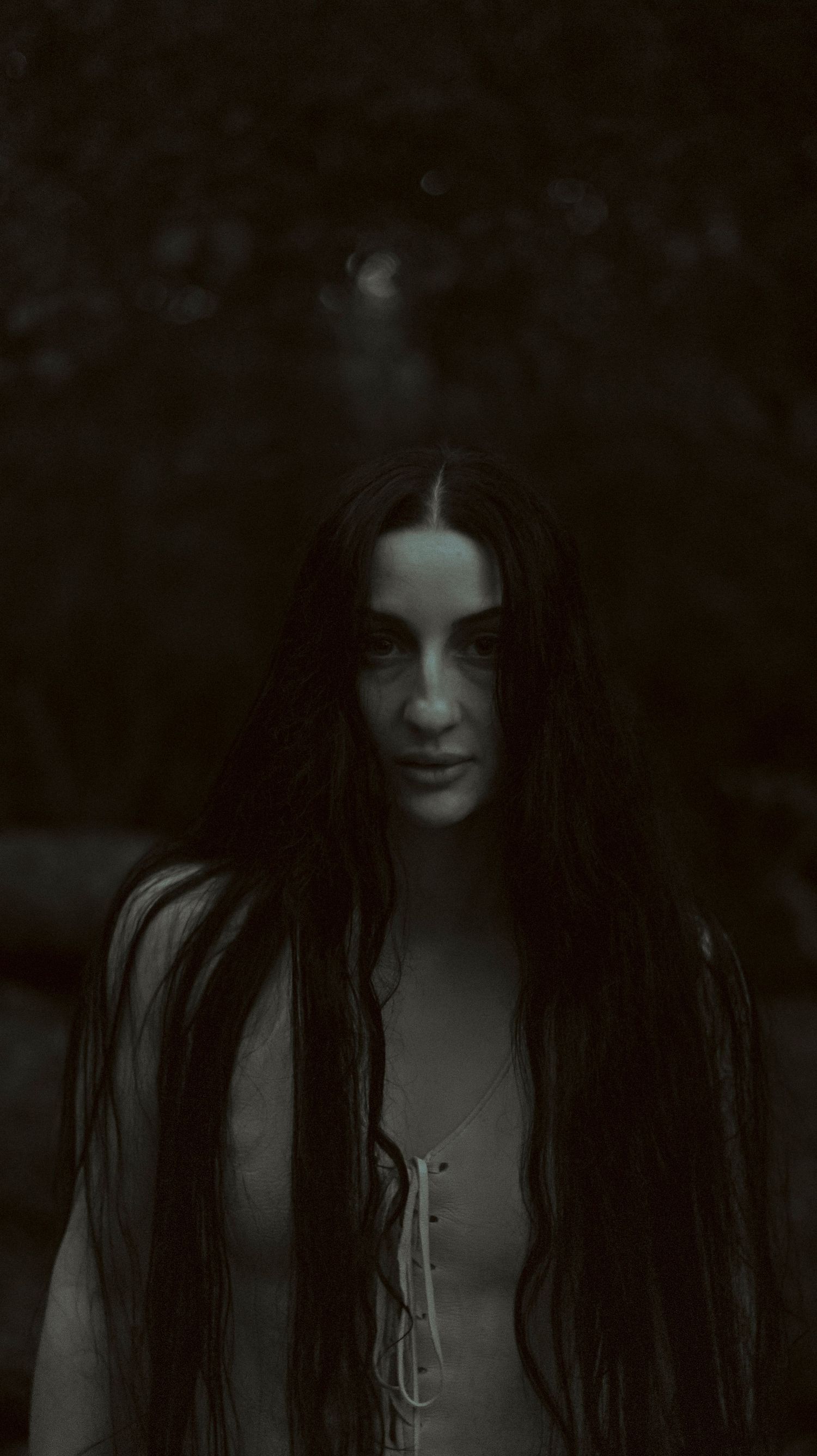 A dark and moody black and white portrait series showing long dark hair against a shadowy background.