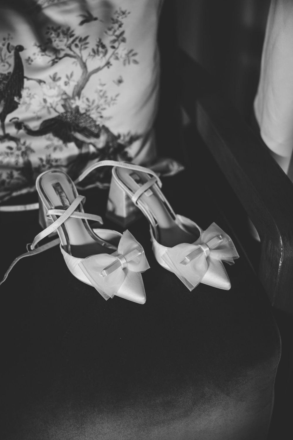 Black and white photo of elegant bridal heels with bow details and ankle straps resting on a velvet chair. Markree Castle Sligo