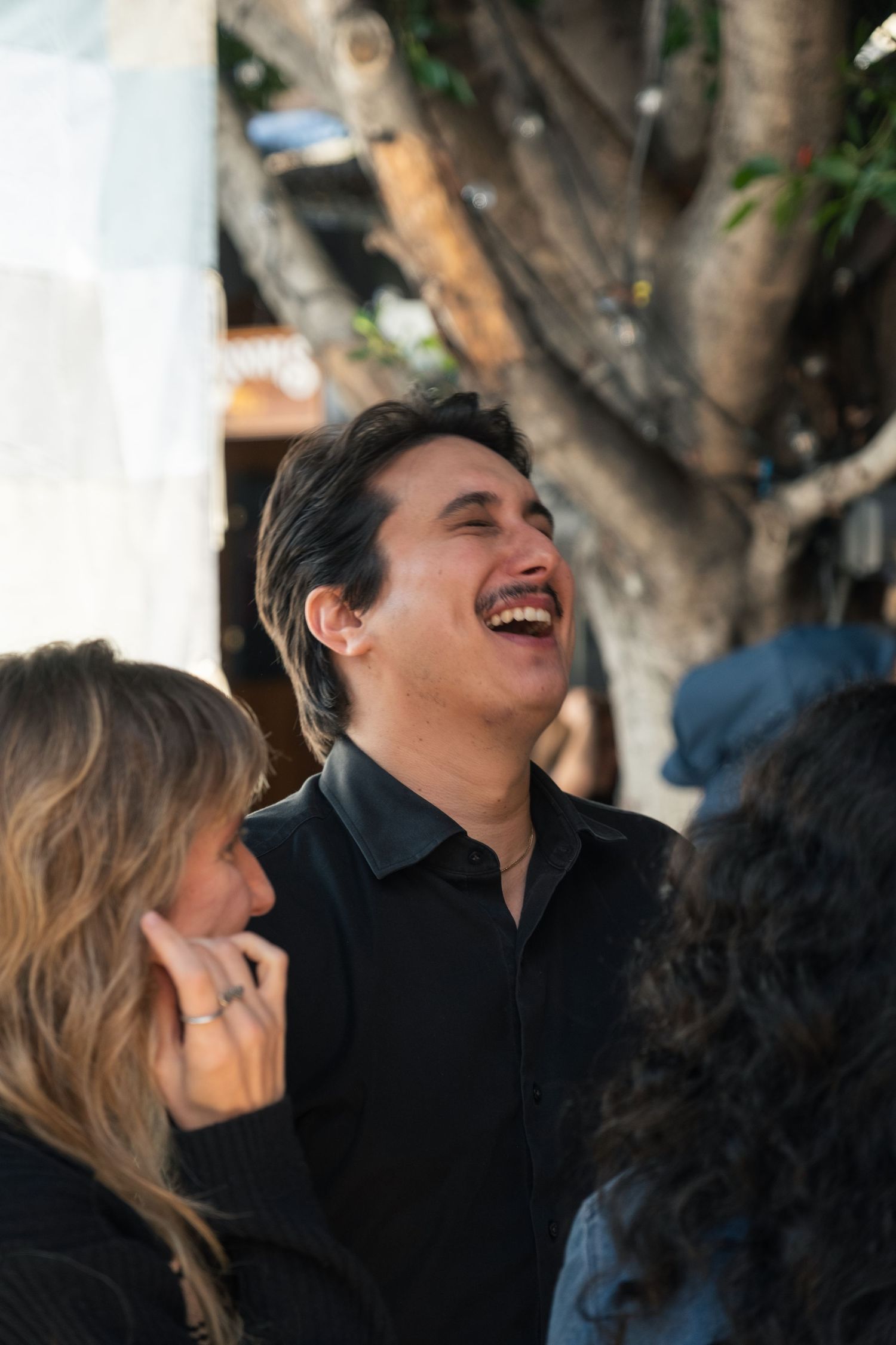 A group of friends share a candid moment of laughter outdoors on a sunny day.
