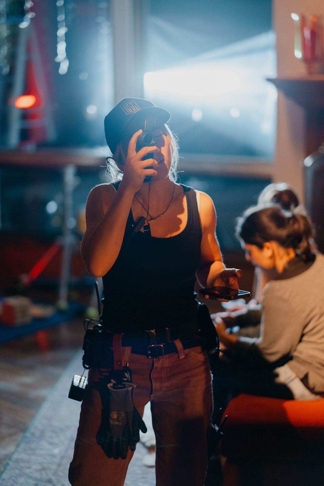 Dramatic lighting illuminates a performer in a dark venue wearing black attire.