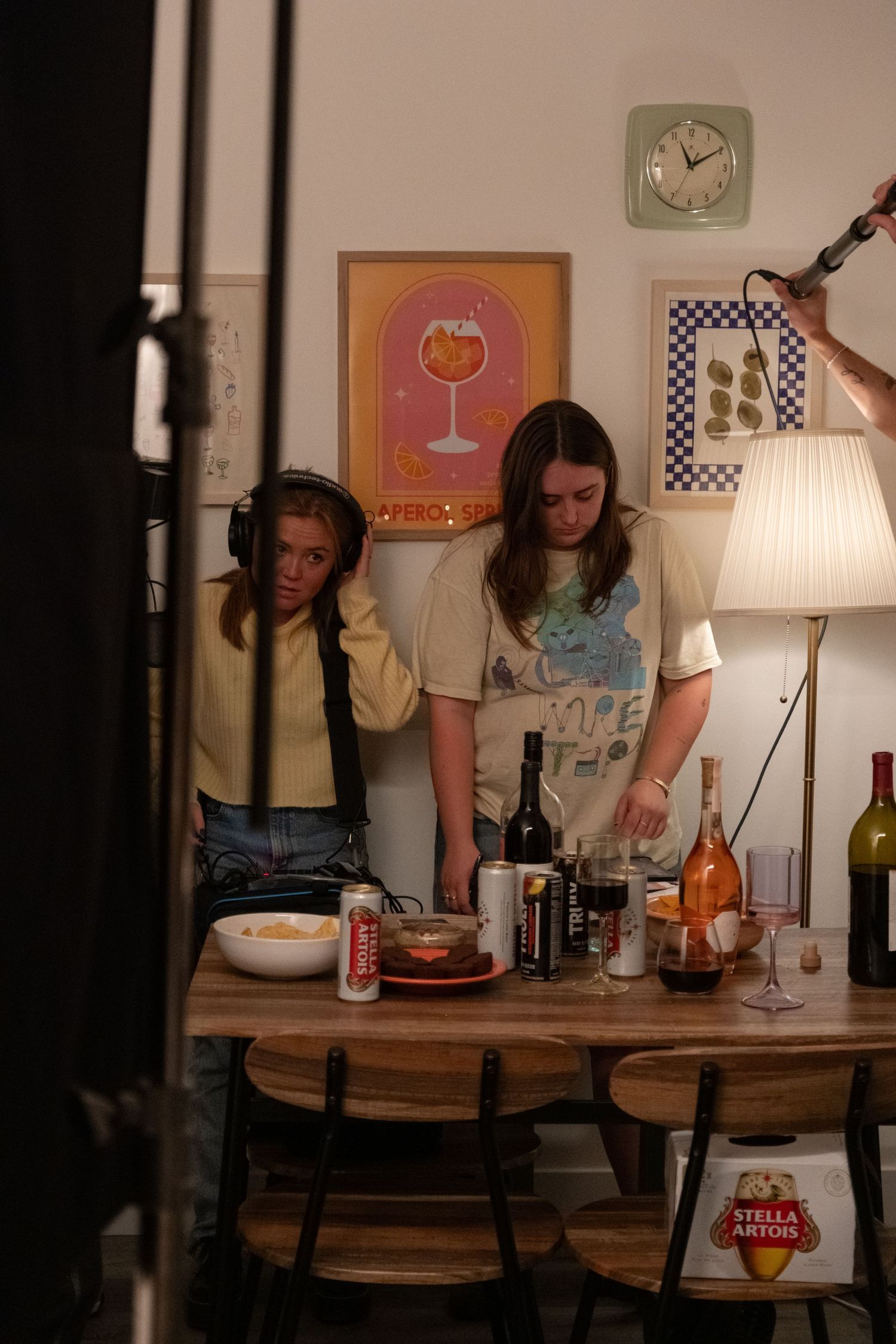 Casual gathering in a dining room with wall art and table lamp visible.