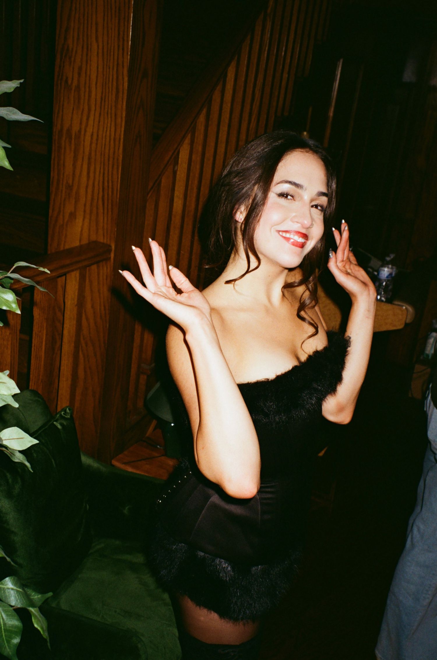 Woman in black dress dancing joyfully in dimly lit venue.