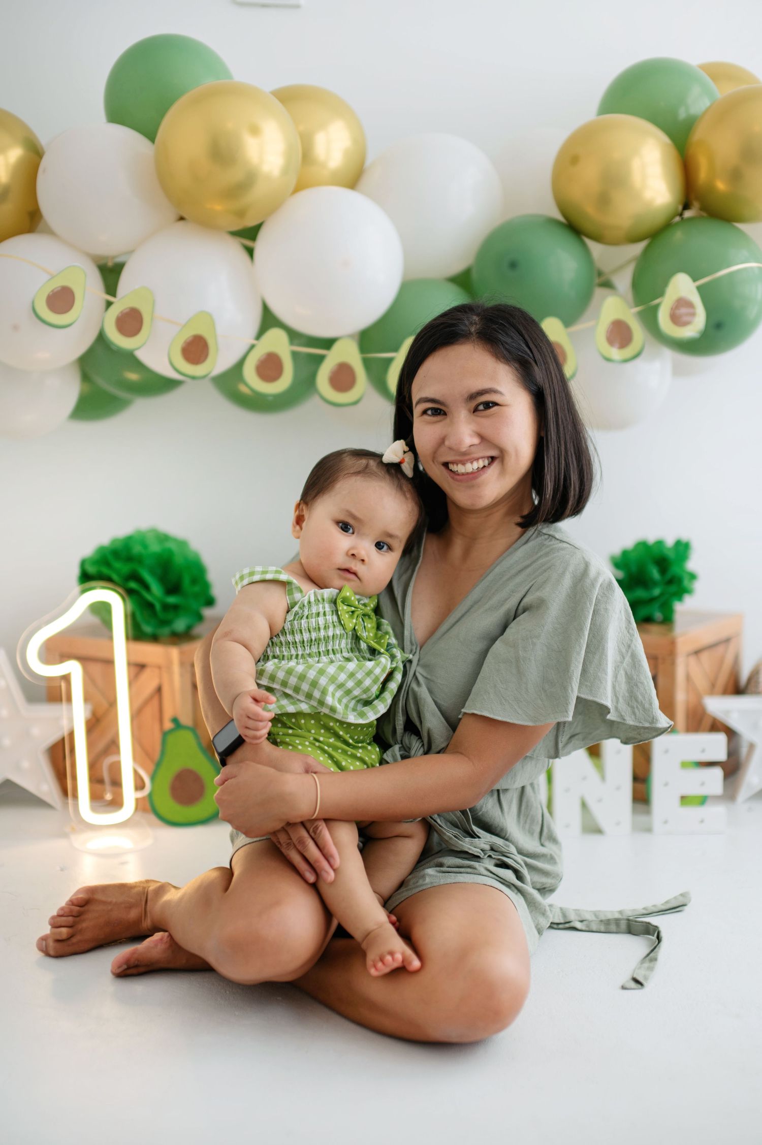 Candid family portraits with avocado-themed decor and festive balloon garland in green and gold.