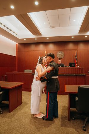A bride and Marine celebrate their courthouse wedding with a romantic dance in a wood-paneled room.